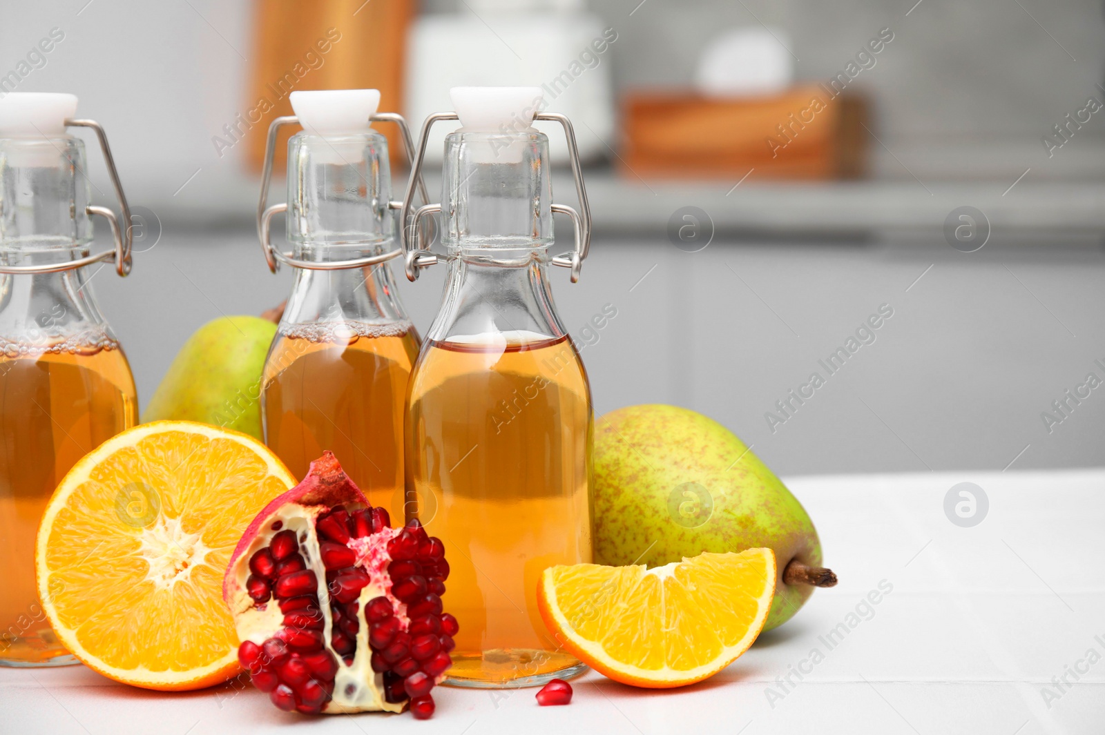 Photo of Homemade fermented kombucha and fresh fruits on white table in kitchen. Space for text