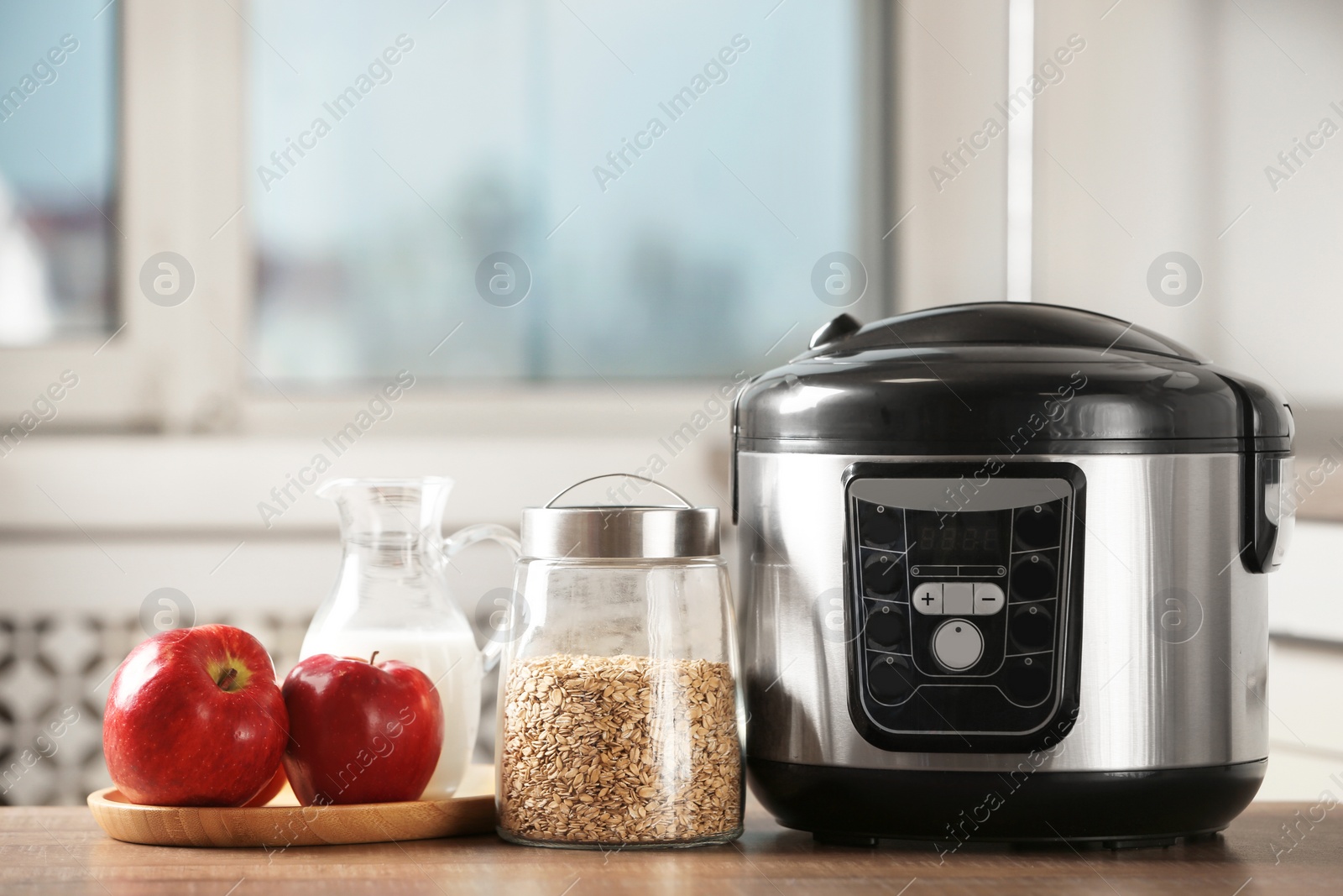 Photo of Modern multi cooker and products on table in kitchen. Space for text