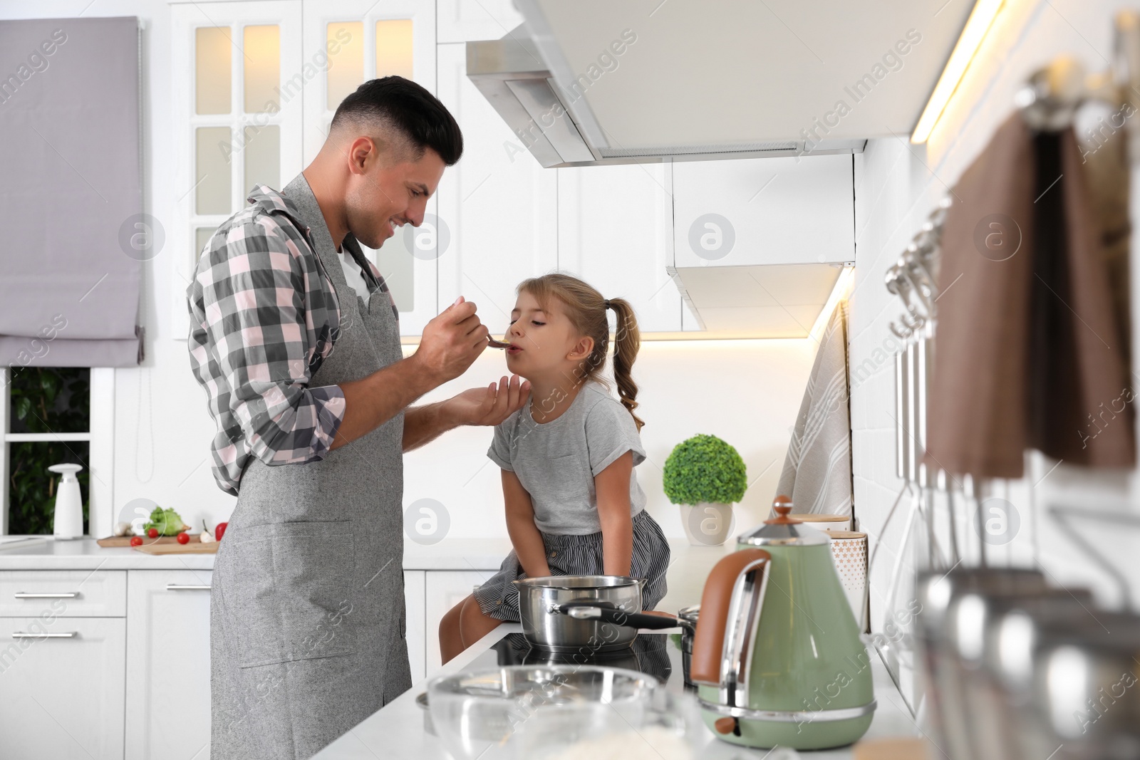 Photo of Little girl with her father cooking together in modern kitchen