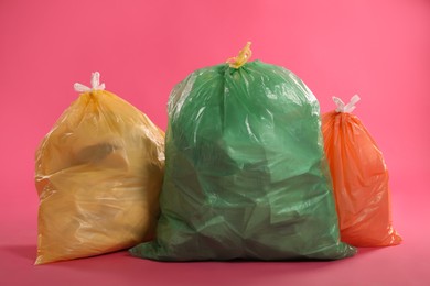 Photo of Trash bags full of garbage on pink background