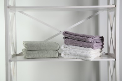 Photo of Stacks of soft towels on shelf indoors