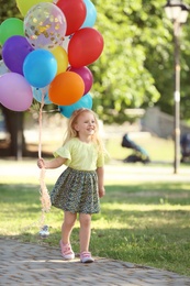 Cute girl with colorful balloons in park on sunny day