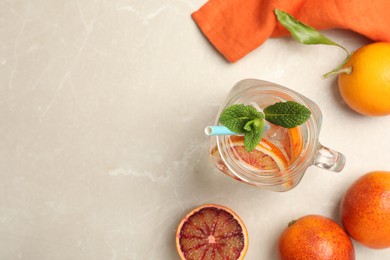 Photo of Delicious refreshing drink with sicilian orange and mint on grey table, flat lay. Space for text