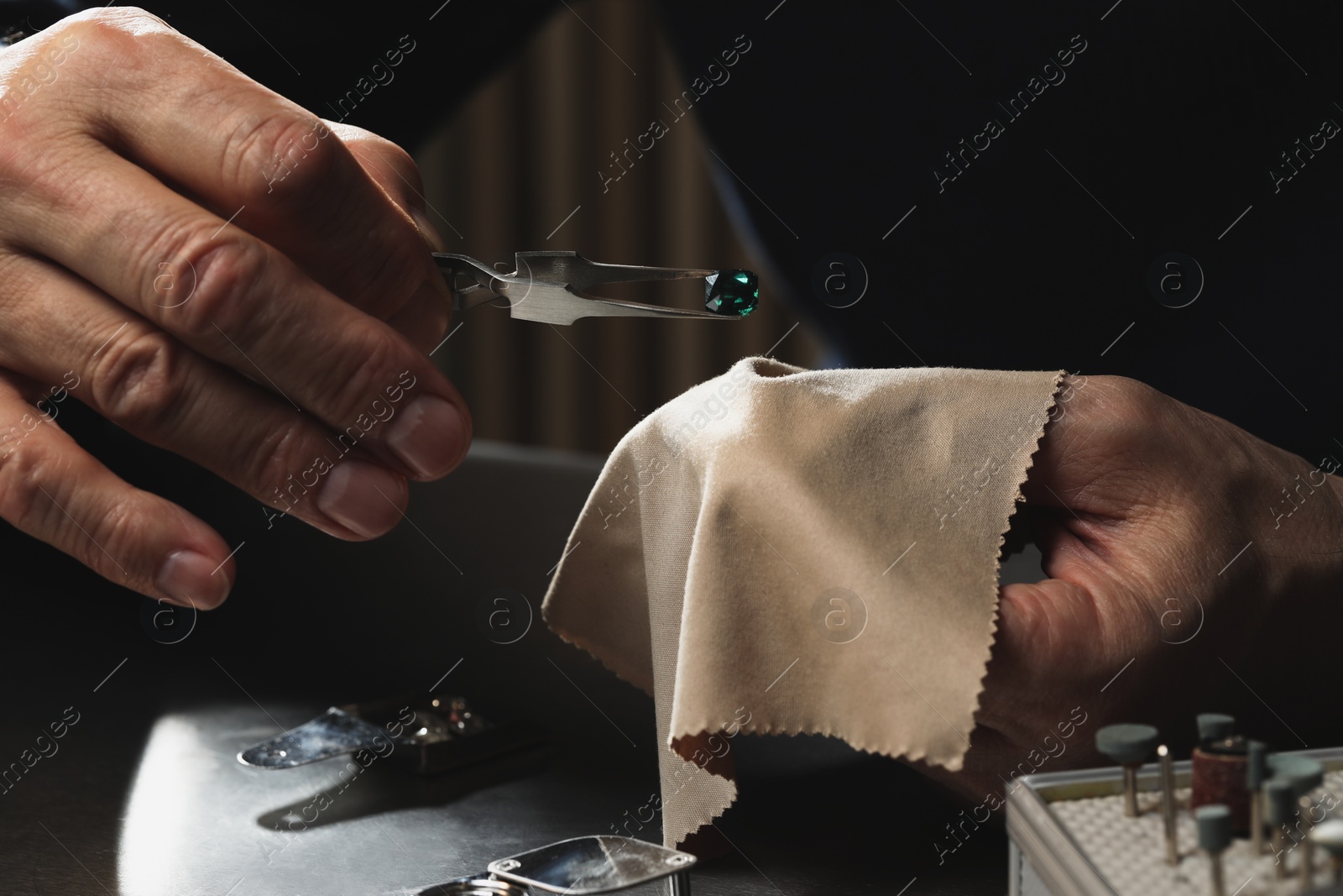 Photo of Professional jeweler working with gemstone at table, closeup