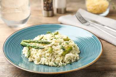 Photo of Delicious risotto with asparagus served on wooden table