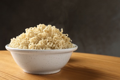 Bowl of hot noodles on table against grey background. Space for text