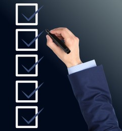 Man with marker and check boxes with ticks on dark background, closeup