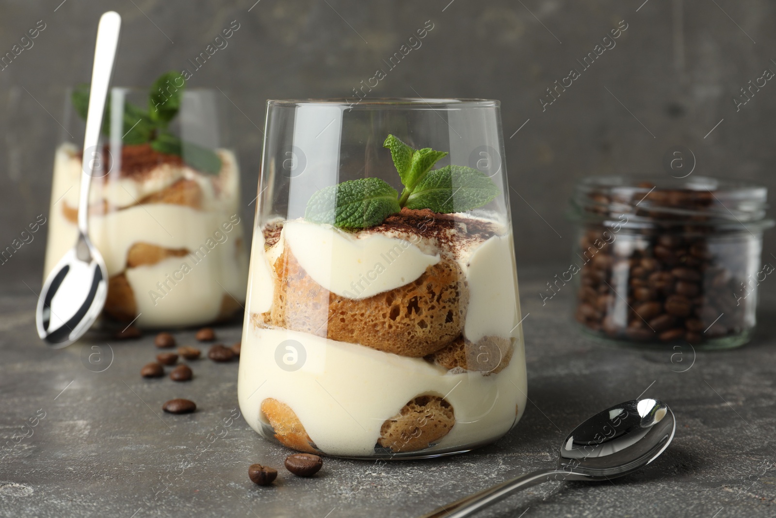 Photo of Delicious tiramisu with mint in glass on grey table