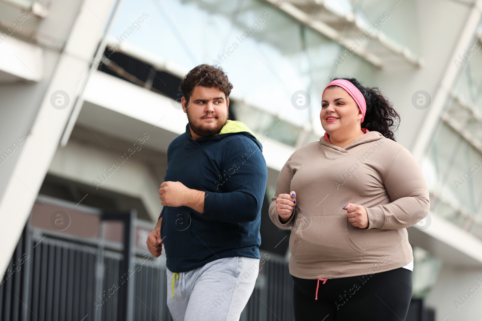 Photo of Overweight couple running together outdoors. Fitness lifestyle