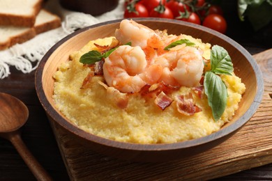 Photo of Fresh tasty shrimps, bacon, grits and basil in bowl on table, closeup