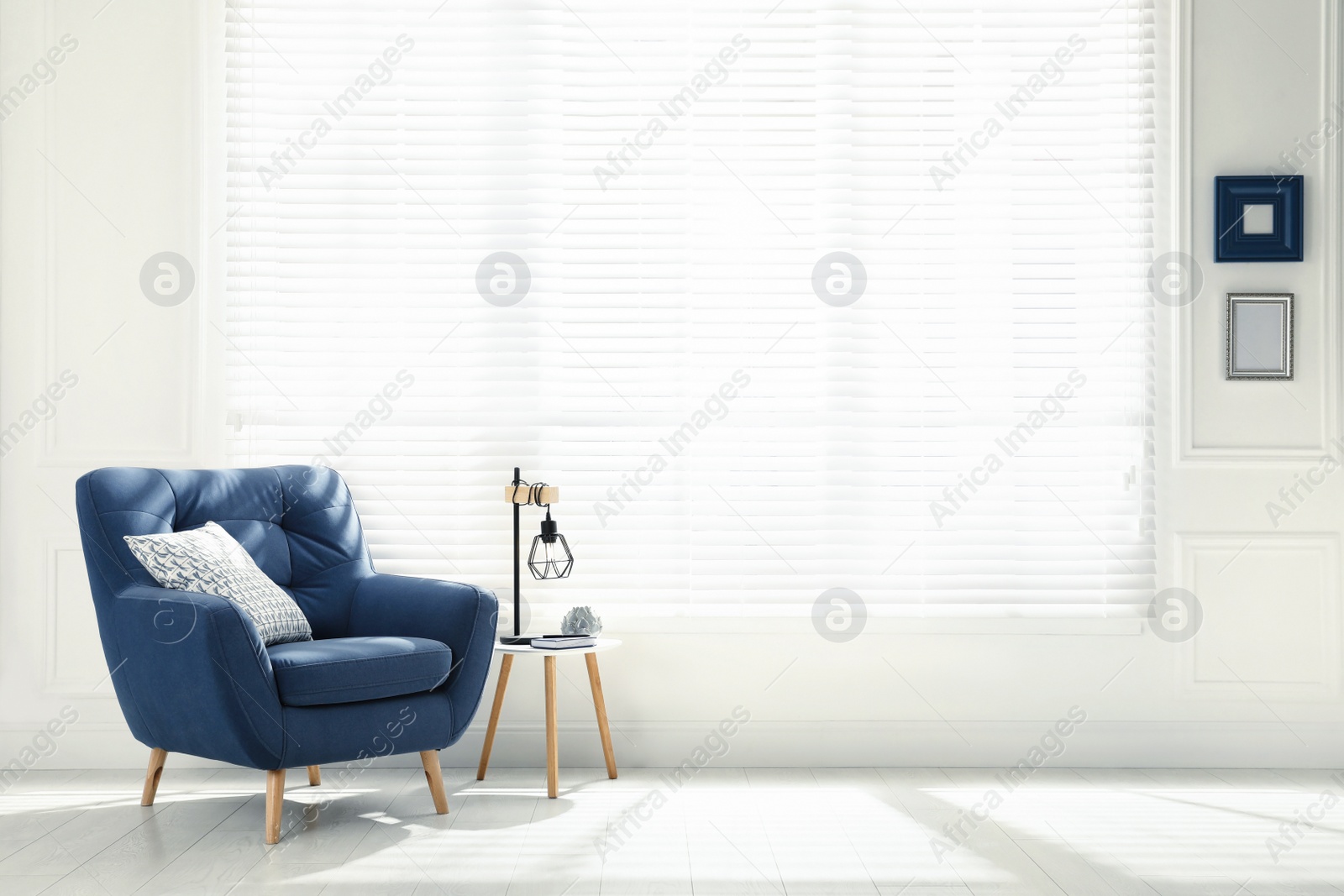 Photo of Comfortable armchair with pillow, stool and lamp near big window in spacious room. Interior design