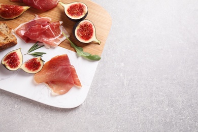 Photo of Delicious ripe figs, prosciutto and toasted bread served on table, top view. Space for text