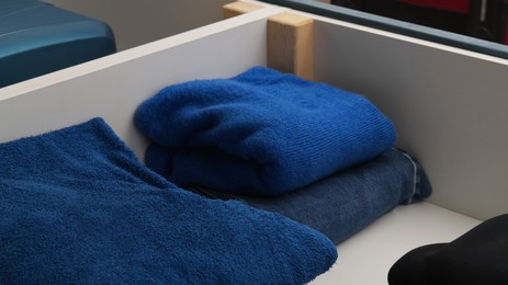 Photo of Storage drawer with bedclothes in room, closeup
