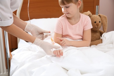 Doctor adjusting intravenous drip for little child in hospital