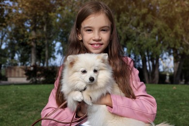 Photo of Little girl with her cute dog in park. Autumn walk