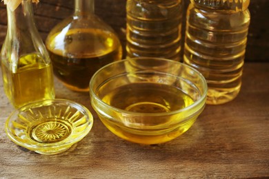 Glass bowls and bottles with sunflower oil on wooden table, closeup