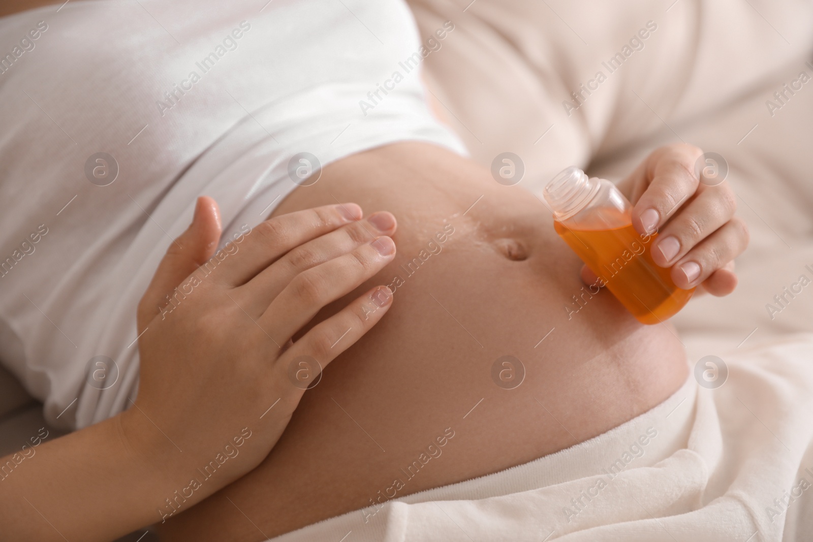 Photo of Young pregnant woman with cosmetic product on sofa, closeup
