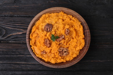 Photo of Bowl with mashed sweet potatoes on wooden background, top view