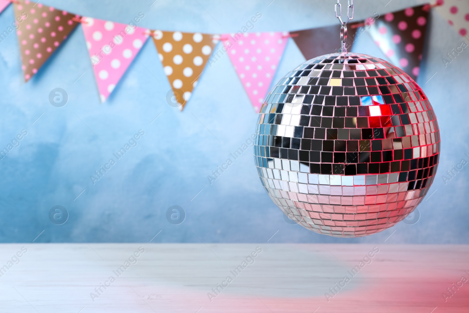 Photo of Shiny disco ball hanging over white table. Space for text