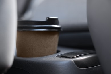 Photo of Coffee to go. Paper cup with tasty drink in holder inside of car, closeup