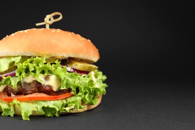 Delicious burger with beef patty and lettuce on dark background, space for text