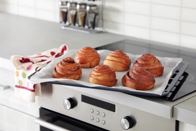 Photo of Tray with freshly oven baked buns on stove in kitchen