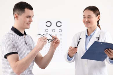 Photo of Vision testing. Young man trying glasses at ophthalmologist office