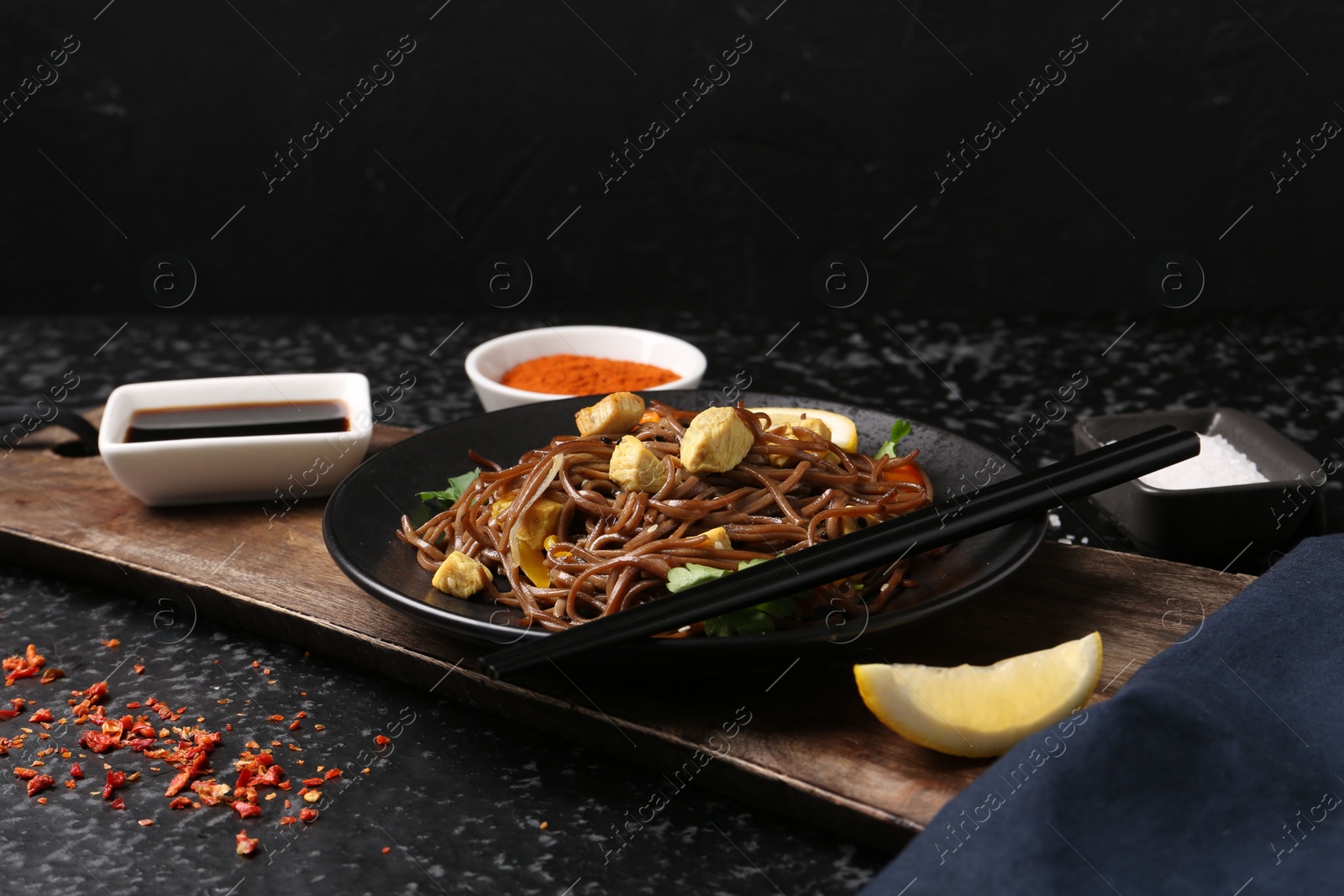 Photo of Stir-fry. Tasty noodles with vegetables and meat served on dark textured table