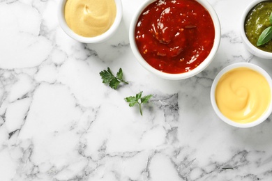 Photo of Set of different delicious sauces on white marble table, top view. Space for text