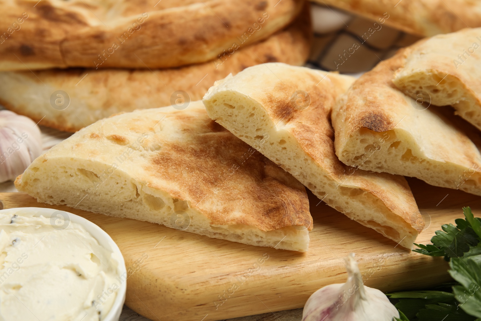 Photo of Pieces of fresh pita bread and cream cheese on table, closeup