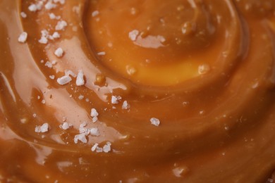 Photo of Delicious caramel sauce with sea salt as background, closeup