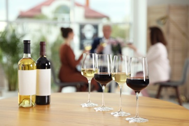 Photo of Bottles and glasses with different wines on table against blurred background