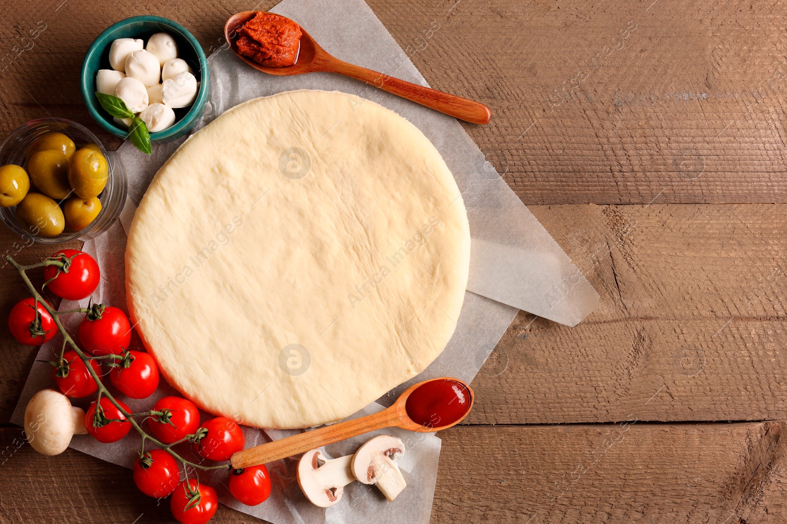 Photo of Pizza dough and products on wooden table, flat lay. Space for text