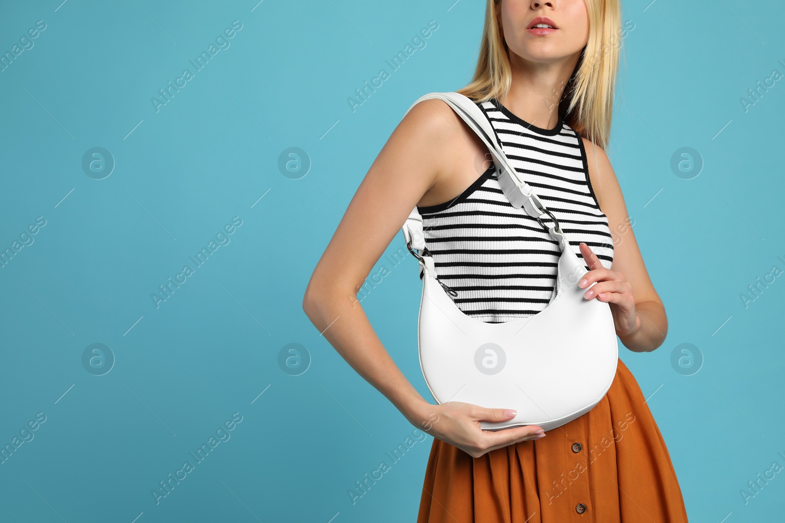Photo of Stylish woman with trendy baguette bag on turquoise background, closeup. Space for text