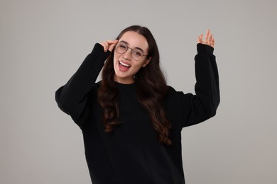 Beautiful young woman in stylish warm sweater on grey background