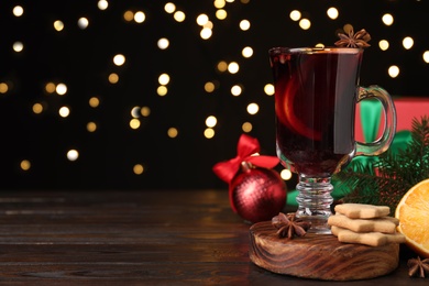 Photo of Christmas composition with cup of mulled wine on wooden table. Space for text