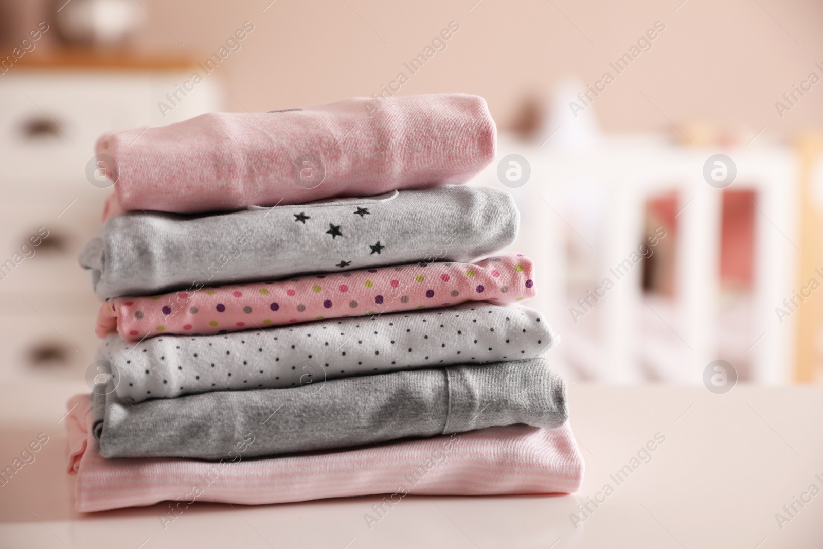 Photo of Stack of clean girl's clothes on table indoors