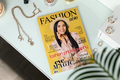 Photo of Fashion magazine and jewelry on white table indoors, flat lay