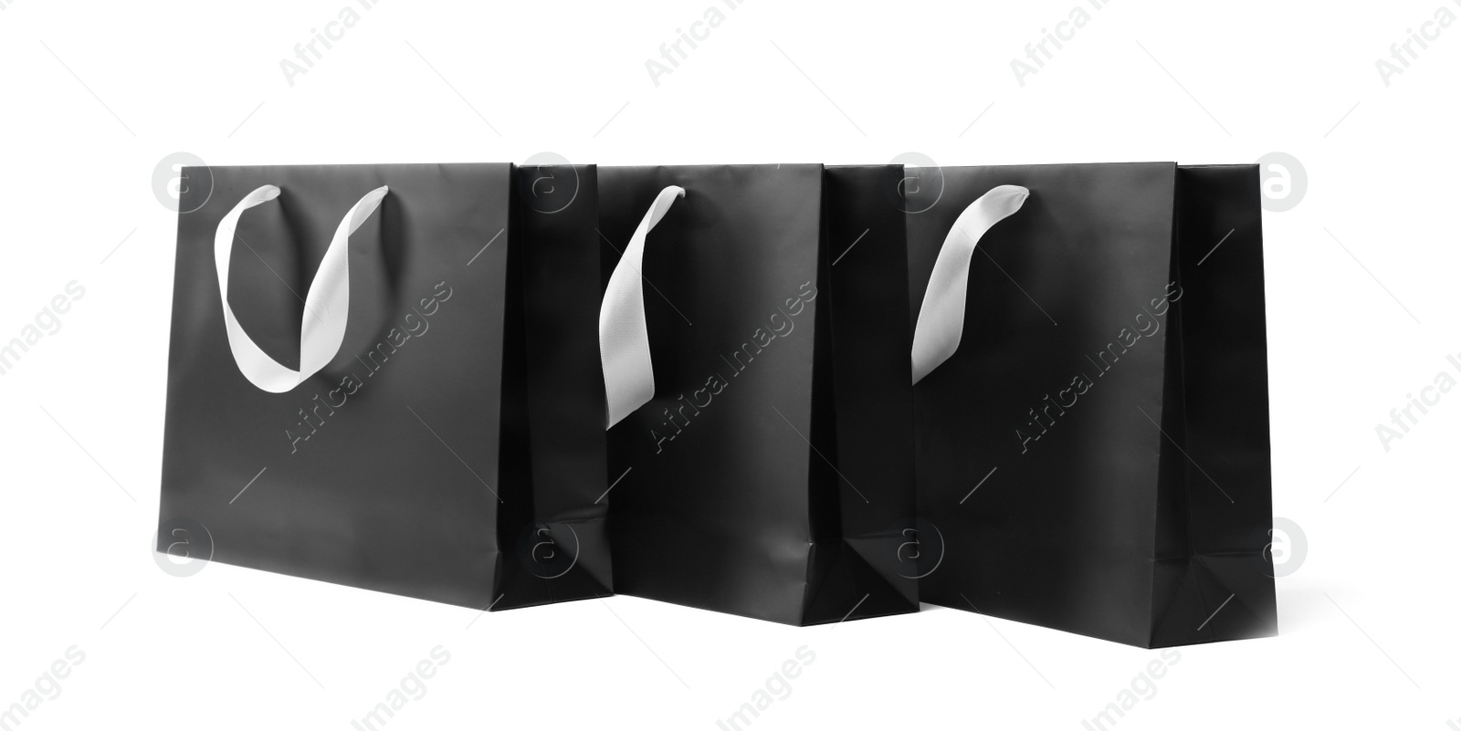 Photo of Paper shopping bags with ribbon handles on white background. Mockup for design