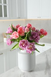 Photo of Beautiful bouquet of colorful tulip flowers on white marble table in kitchen