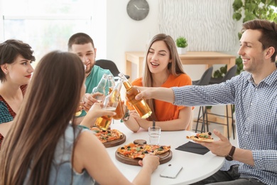 Young people having fun party with delicious pizza indoors