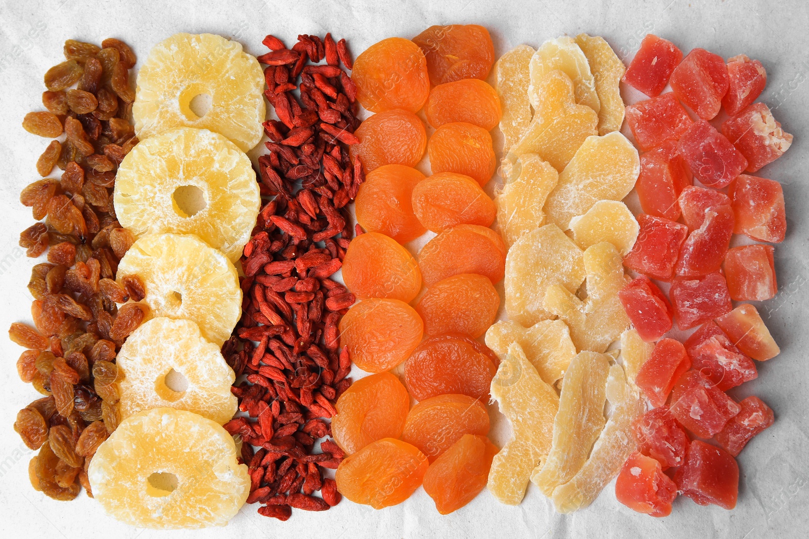 Photo of Different tasty dried fruits on paper, flat lay