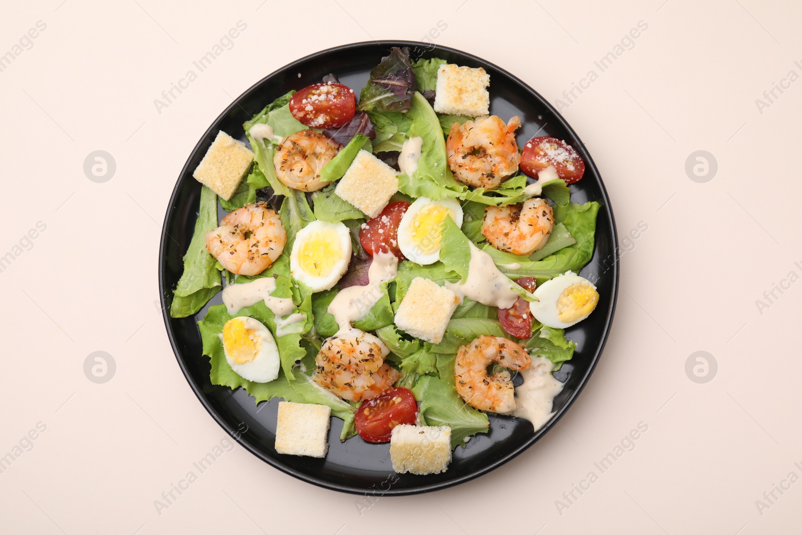 Photo of Delicious Caesar salad with shrimps on beige table, top view