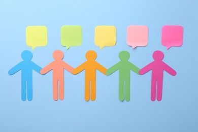Photo of Different human figure and paper speech bubbles on light blue background, flat lay