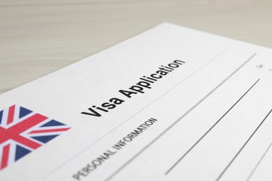 Photo of Immigration to United Kingdom. Visa application form on wooden table, closeup