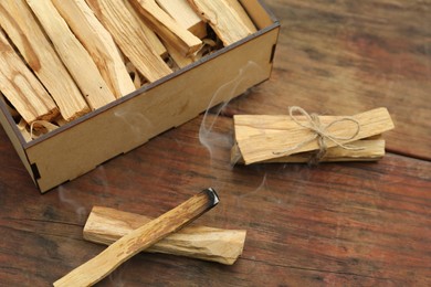 Photo of Many Palo Santo sticks and one smoldering on wooden table, above view