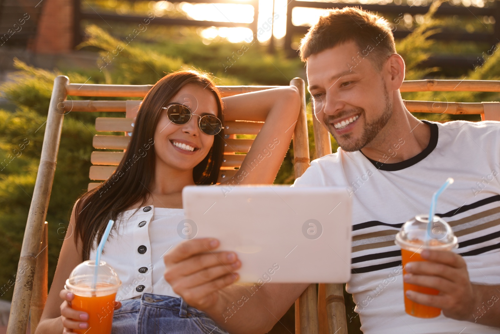 Image of Happy couple with tablet resting together outdoors