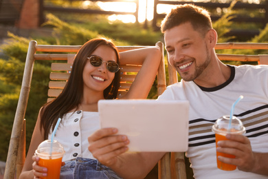 Image of Happy couple with tablet resting together outdoors