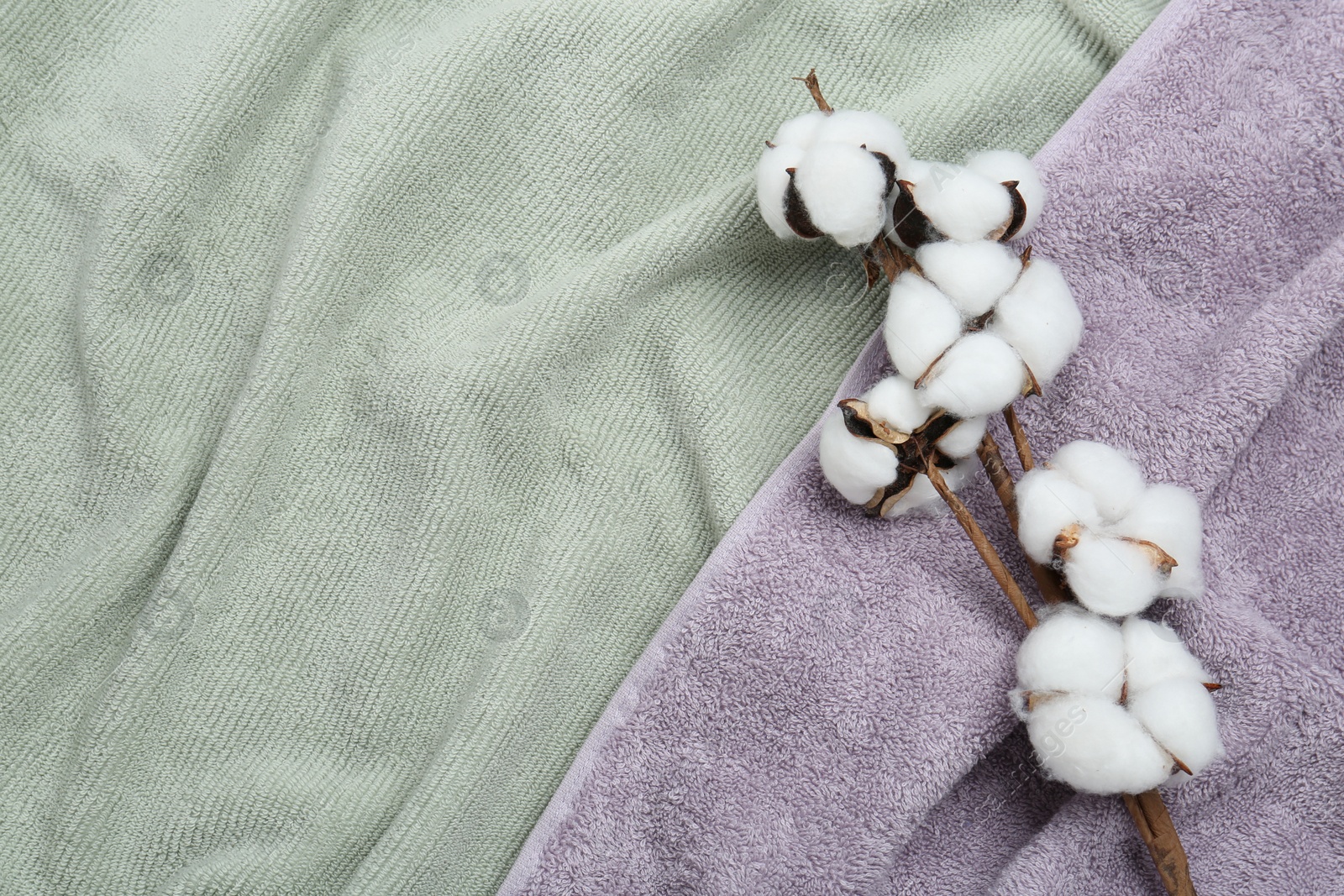 Photo of Cotton flowers on soft towels, top view. Space for text