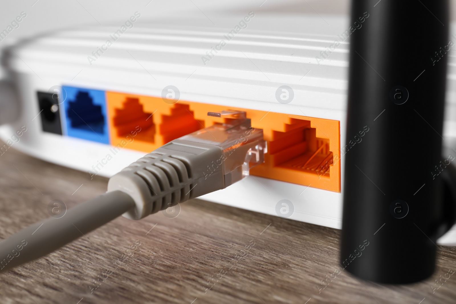 Photo of Connected cable to router on wooden table, closeup. Wireless internet communication